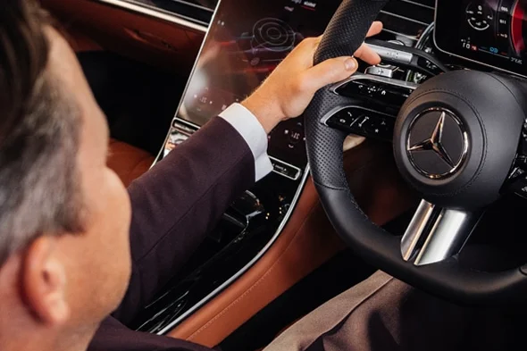 Professional chauffeur at the wheel of a luxury Mercedes — attentive and immaculately presented
